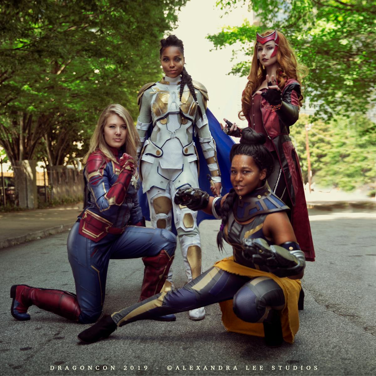 Cosplayers portraying Captain Marvel, Valkyrie, Scarlet Witch, and Shuri from Marvel Cinematic Universe.